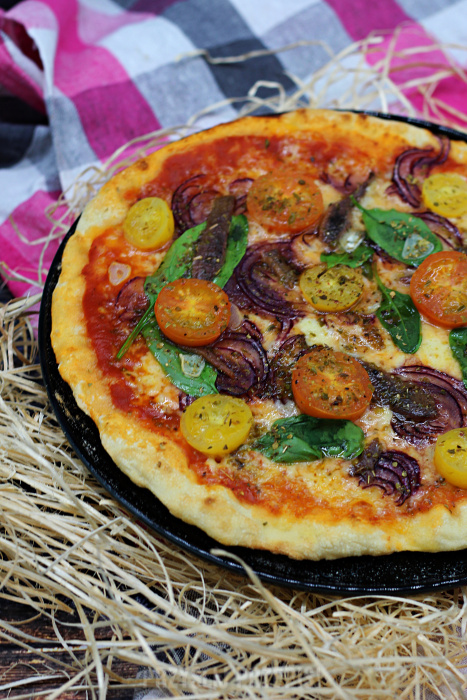 Pizza z anchois, szpinakiem, czerwoną cebulą i pomidorkami koktajlowymi