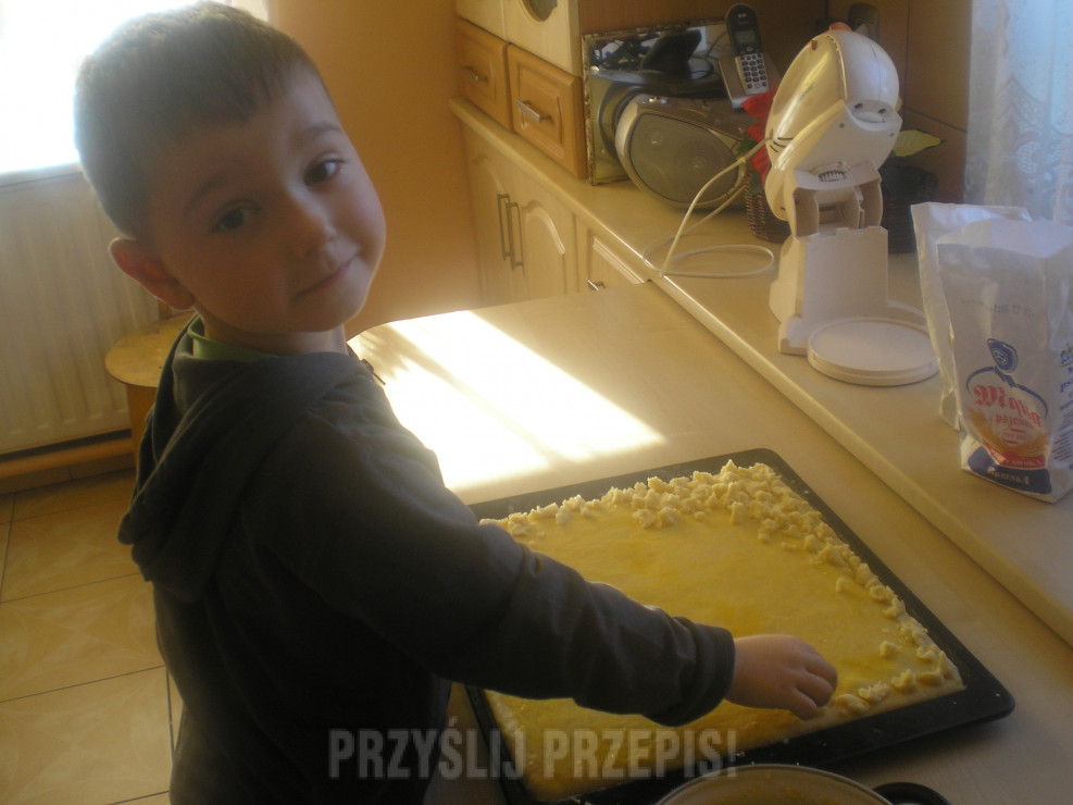 Synek nakłada kruszonkę na ciasto