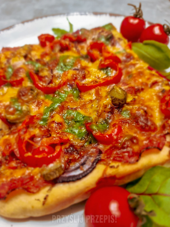 Pizza na grubym cieście, z salami, czerwoną cebulą, papryką i ogórkiem konserwowym